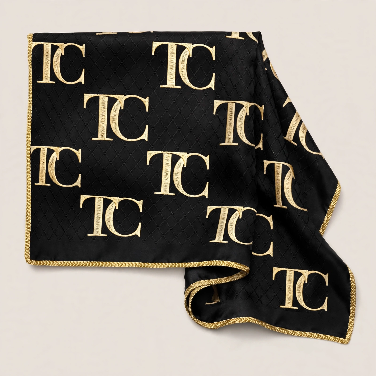 Black quilted head scarf with a repeating gold TC monogram and braided gold edge